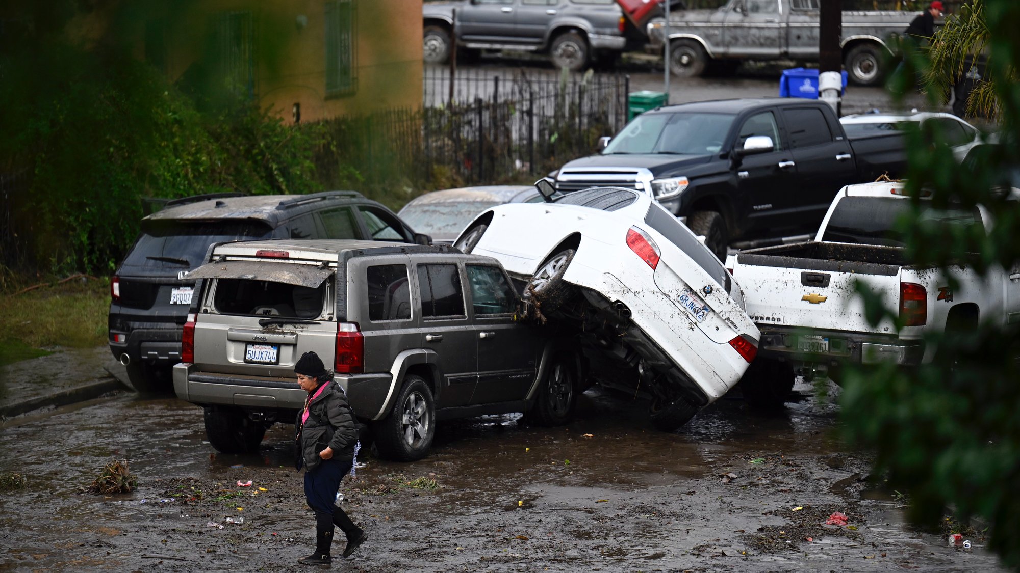 A woman walks by cars damaged by floods during a rainstorm in San Diego on Monday, Jan. 22, 2024. (AP Photo_Denis Poroy)