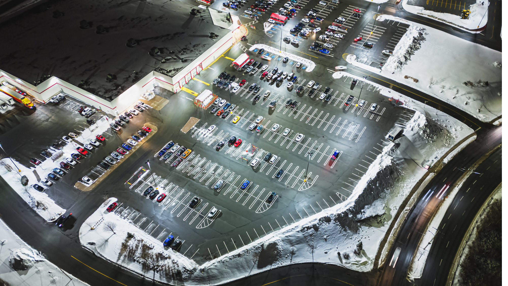 Cars in a snowy parking lot outside a retail store.