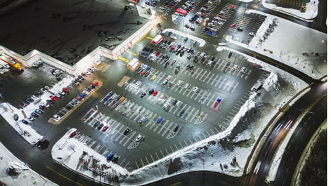 Photo of cars in a snowy parking lot outside a retail store.