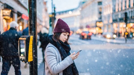 Woman on the phone as snow falls in city