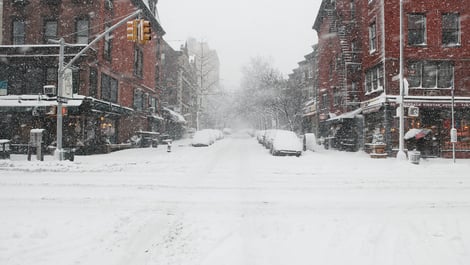 Snow covered urban street intersection in a snow storm with snow covered street, car, buildings, stores, street lights with snow falling on an urban location for blizzard, snow day, snowed in, dangerous conditions, safety