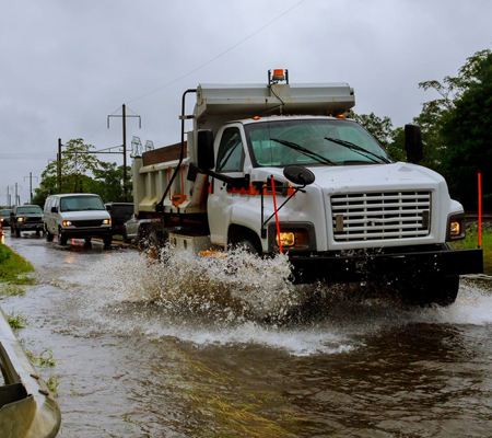 Emergency management vehicles driving through floodwaters
