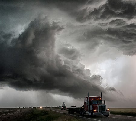 Tractor trailer semi driving under a stormy sky